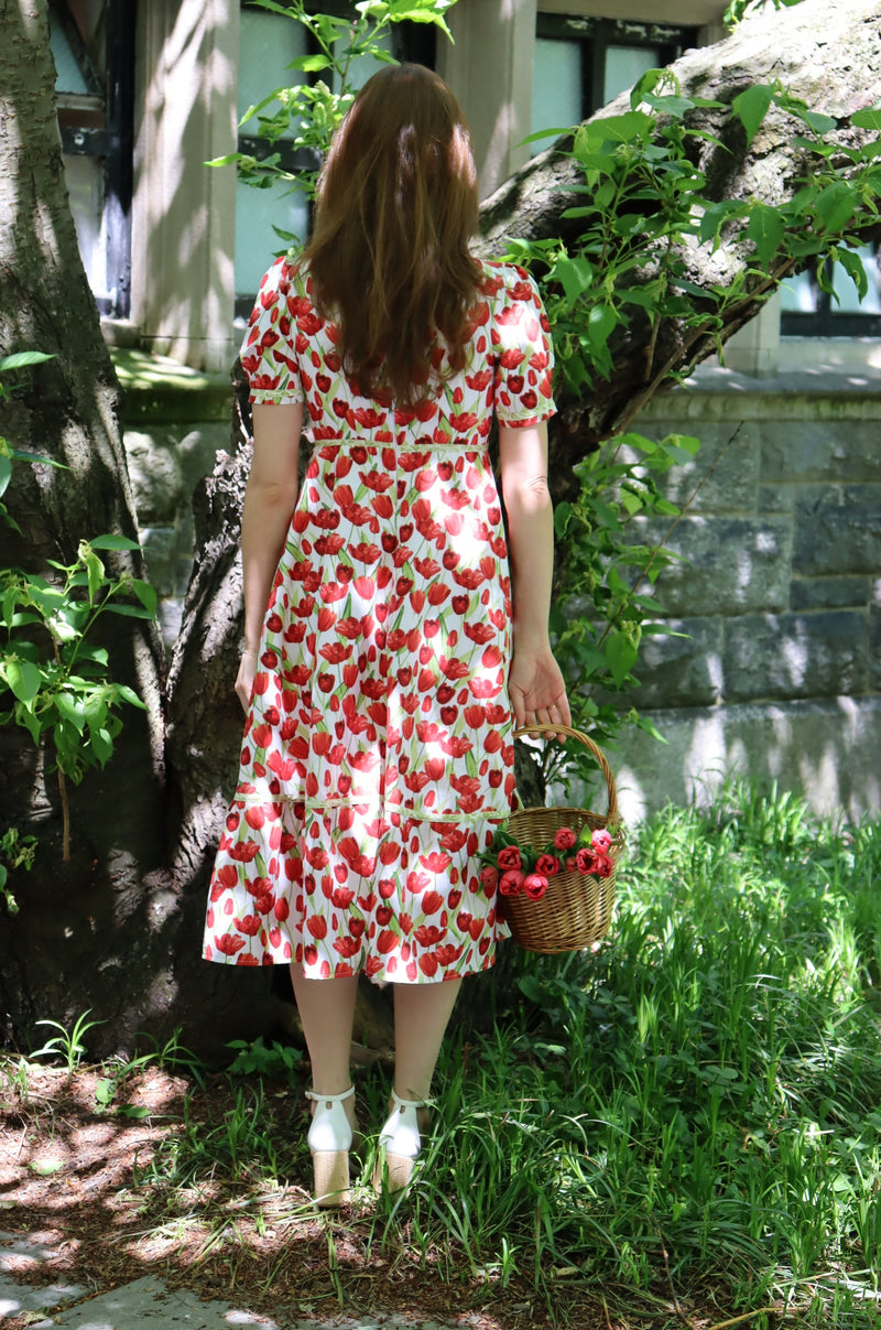 Back of model wearing midi length dress with a tulip print on white.