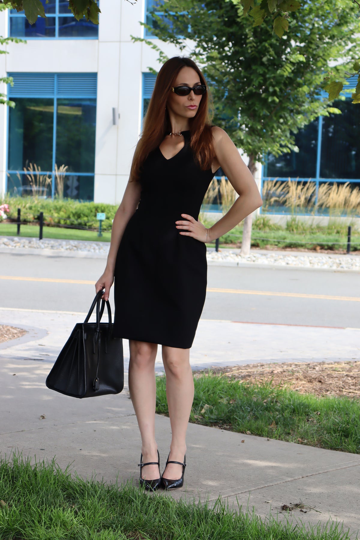 Model wearing our Black Snaffle Bit Keyhole Ponte Dress, with her hand on her waist serving looks, and styled with all black accessories.