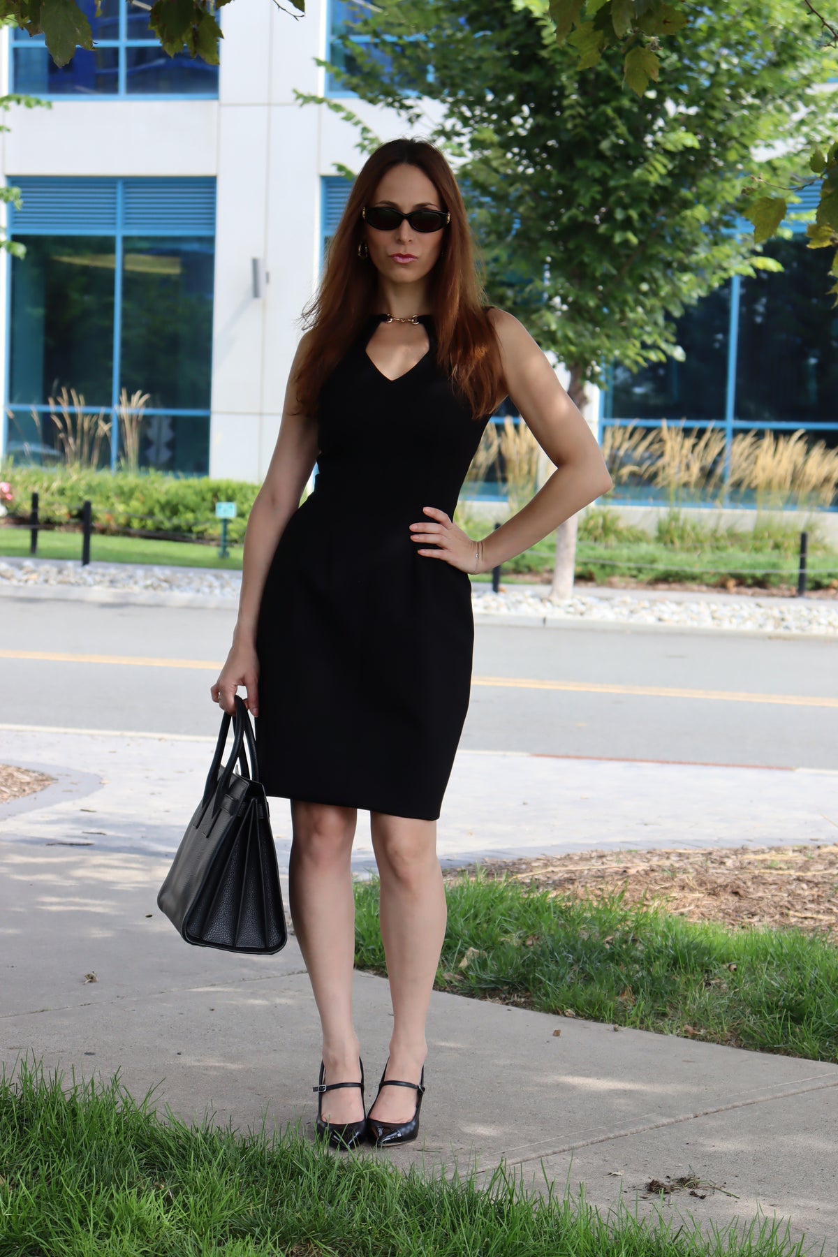 Model wearing our Black Snaffle Bit Keyhole Ponte Dress, with her hand on her waist serving looks, and styled with all black accessories.