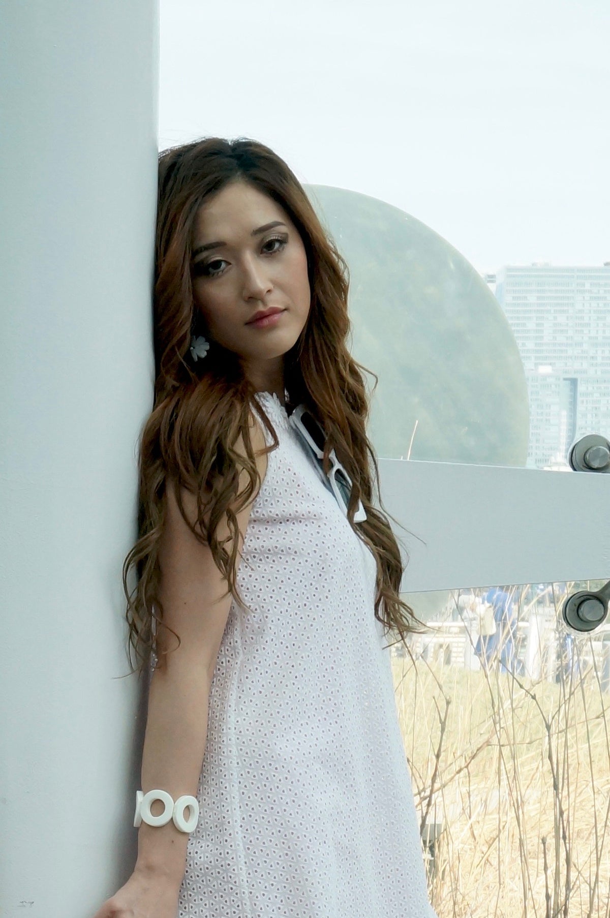 Close up of model wearing an eyelet tent style dress with a peek through bubblegum lining, with a scalloped hem, and a daisy embroidered trim.