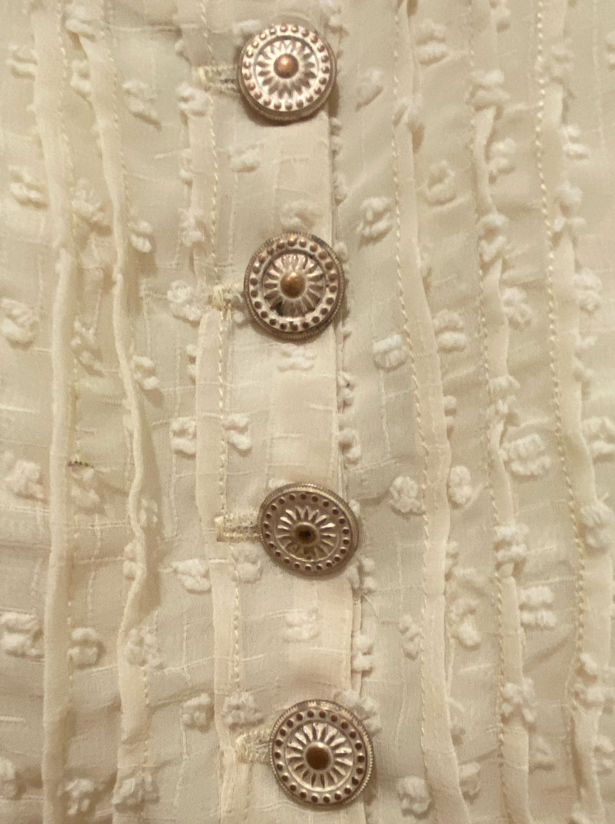 Close up of Swiss Dot fabric with gold buttons.
