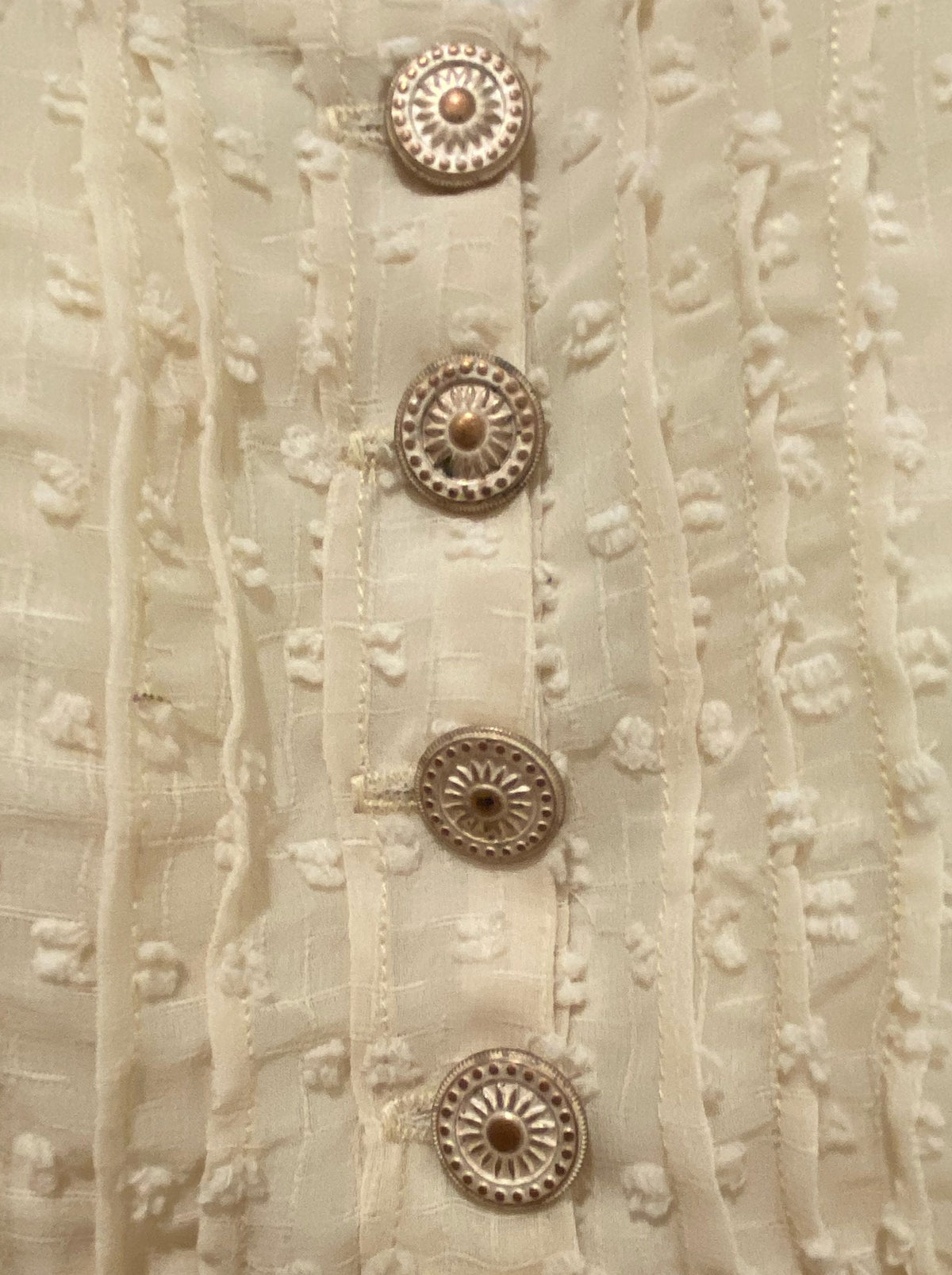 Close up of Swiss Dot fabric with gold buttons.