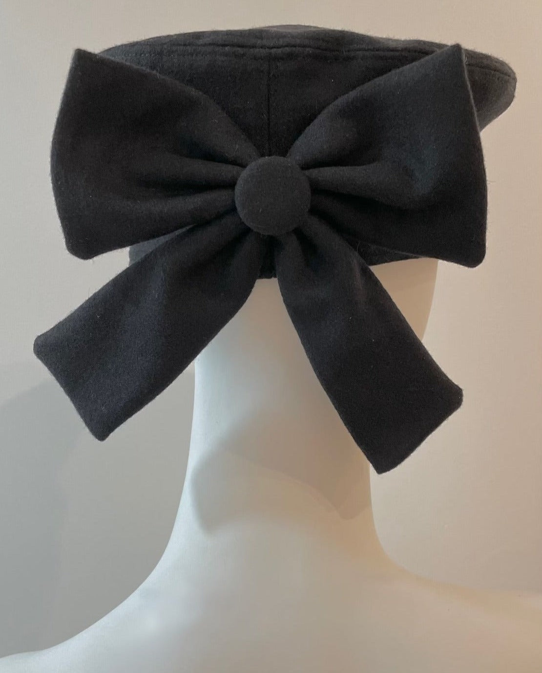 Back of mannequin wearing black bow beret.