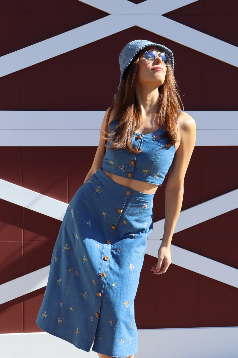 Model wearing Flower Child floral embroidered denim Crop Top in front of a barn.