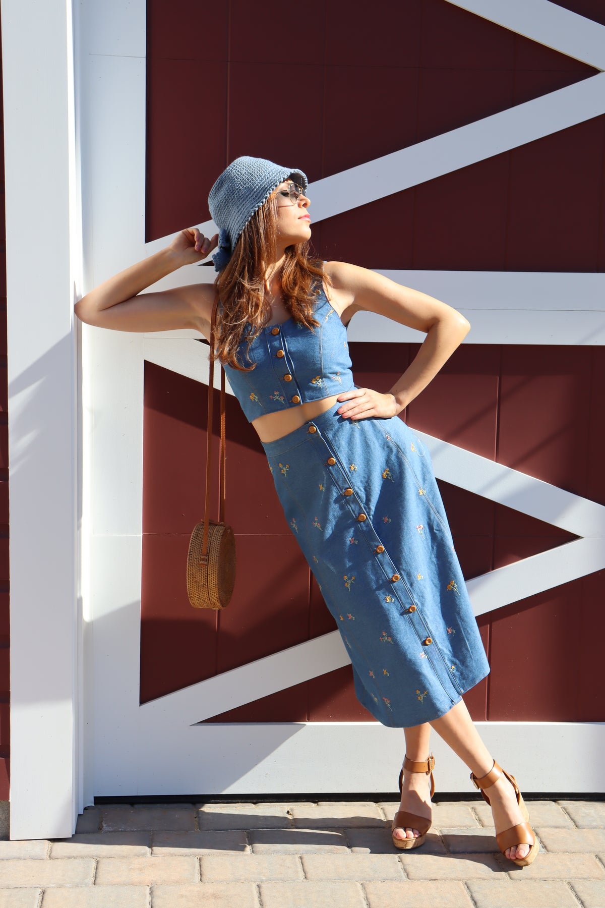 Model leaning on wall in front of a barn wearing Flower Child floral embroidered denim Crop Top.
