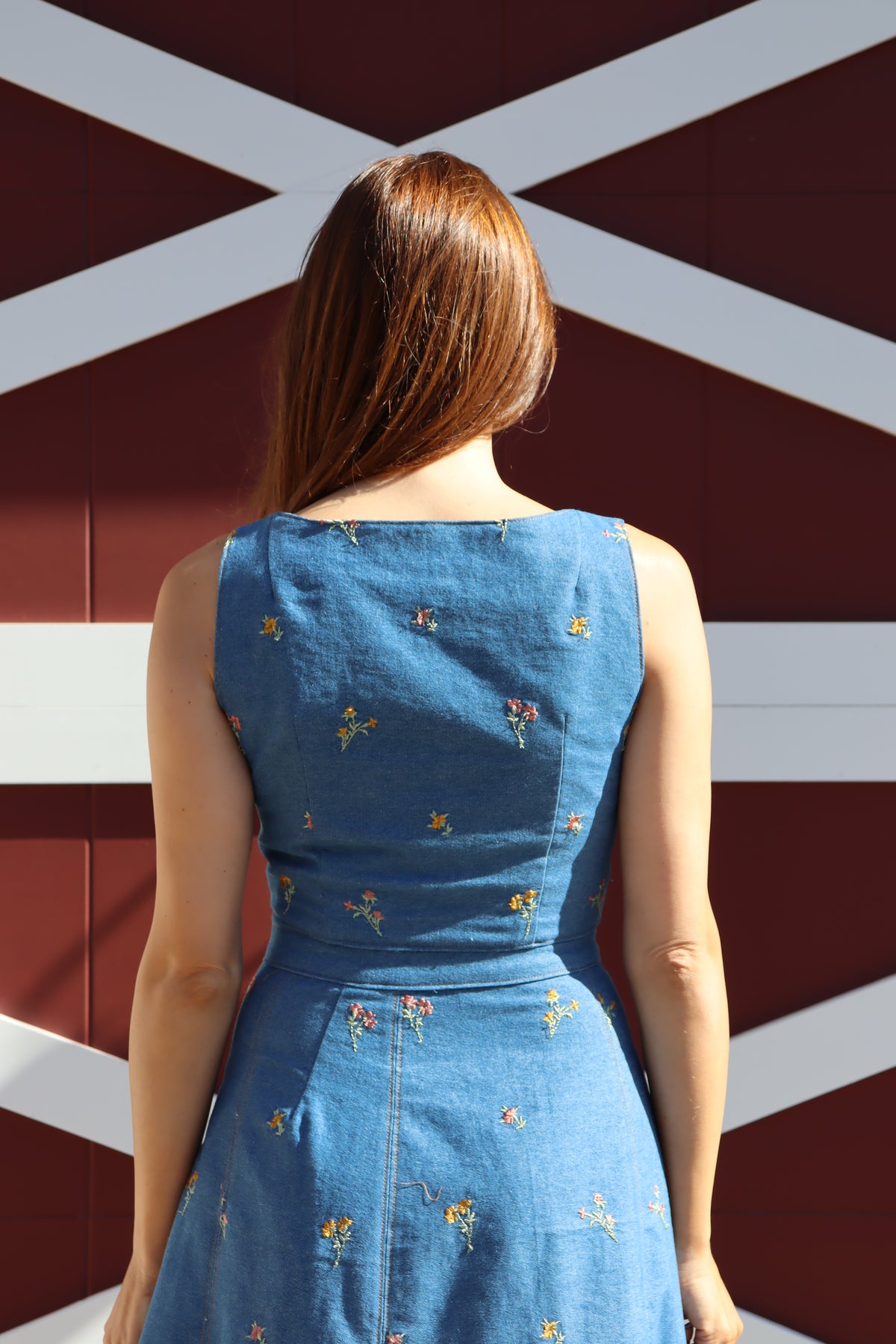 Back view of model wearing Flower Child floral embroidered denim Crop Top.
