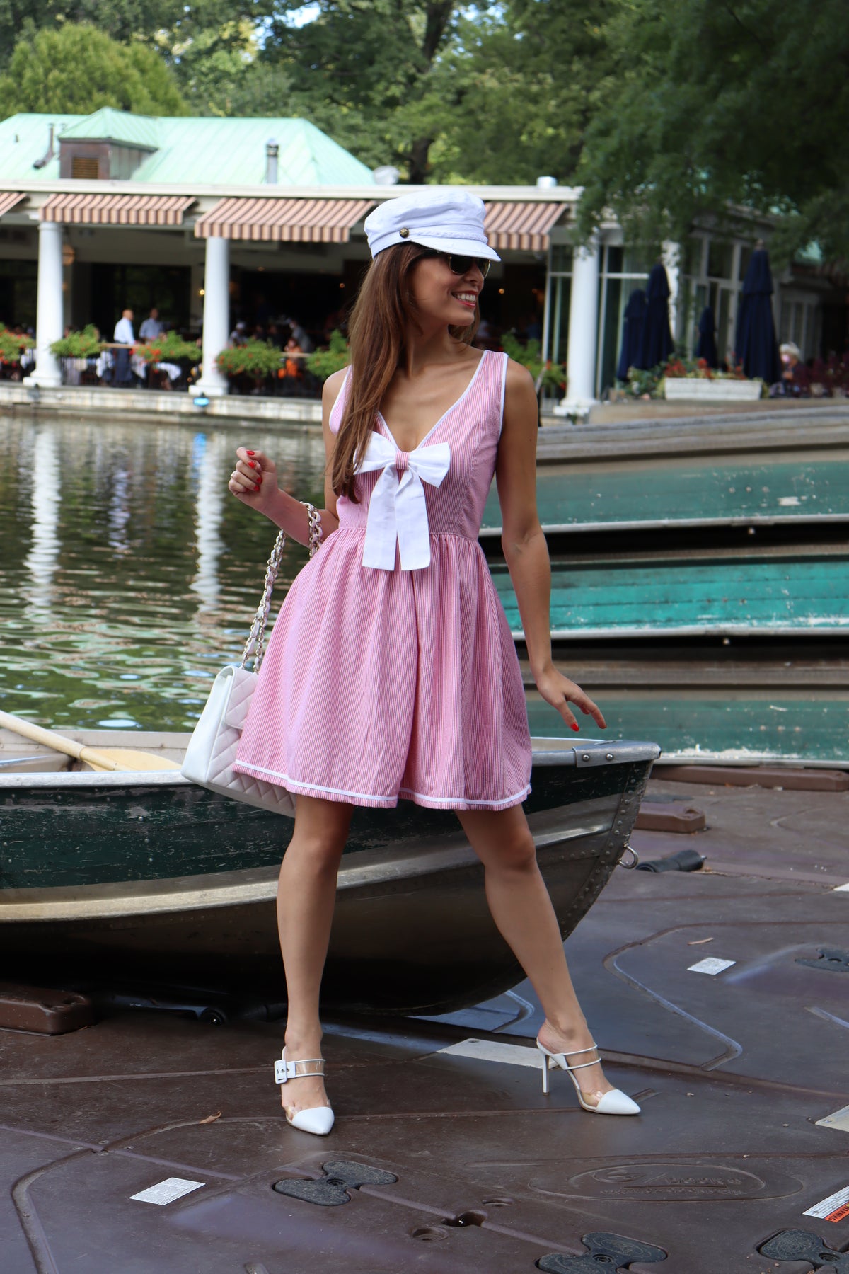 Model wearing red and white pinstriped cotton seersucker with white bow and a white hat looking off to the side smiling.