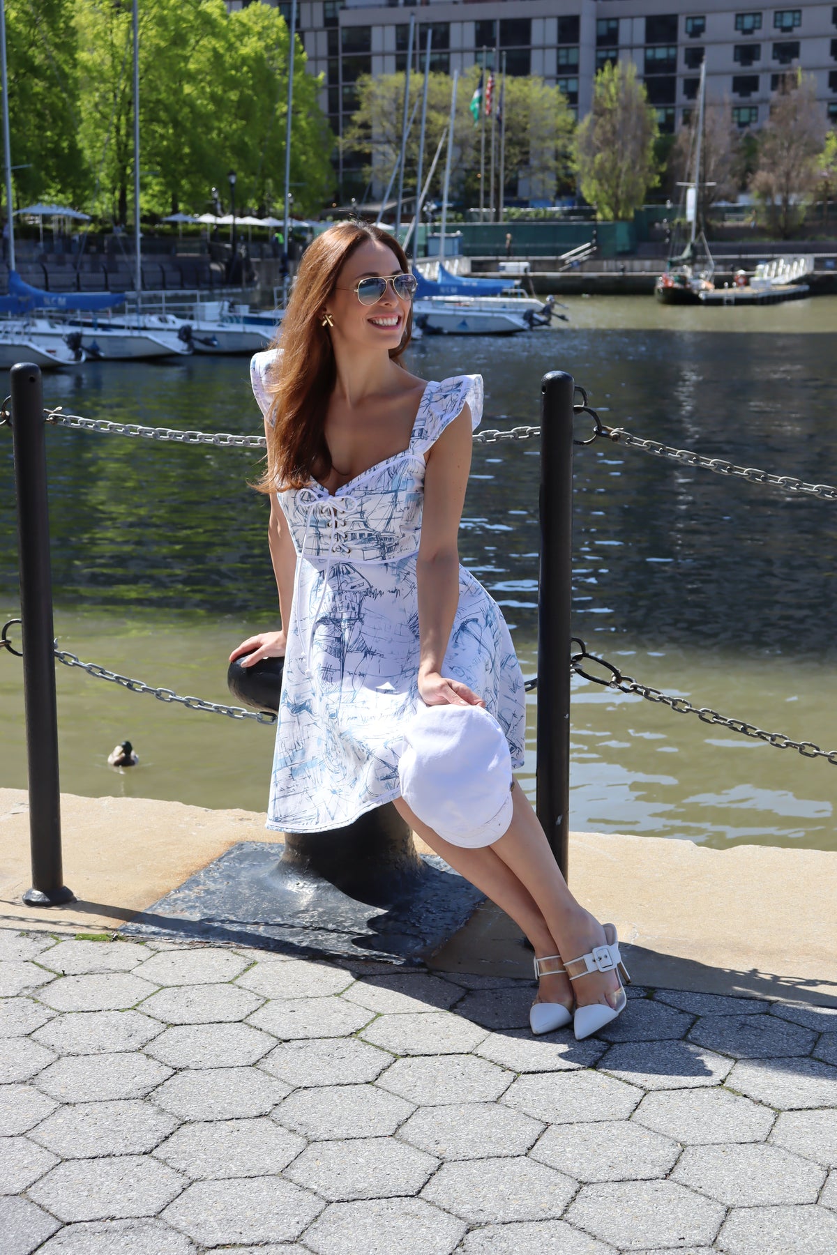 Model wearing heavy toile schooner print sitting in front of water holding a hat and smiling.