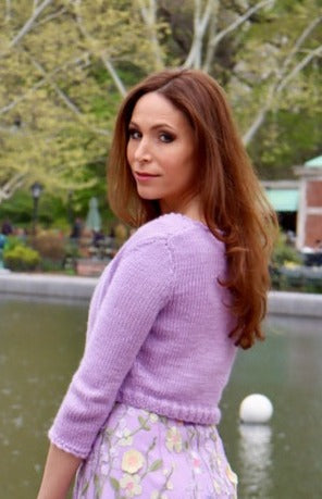 Model standing to the side looking off the shoulder in lilac cropped sweater.