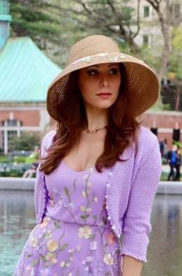 Model in lilac cropped sweater with matching lilac appliquéd floral dress and floral detailed straw sun hat.