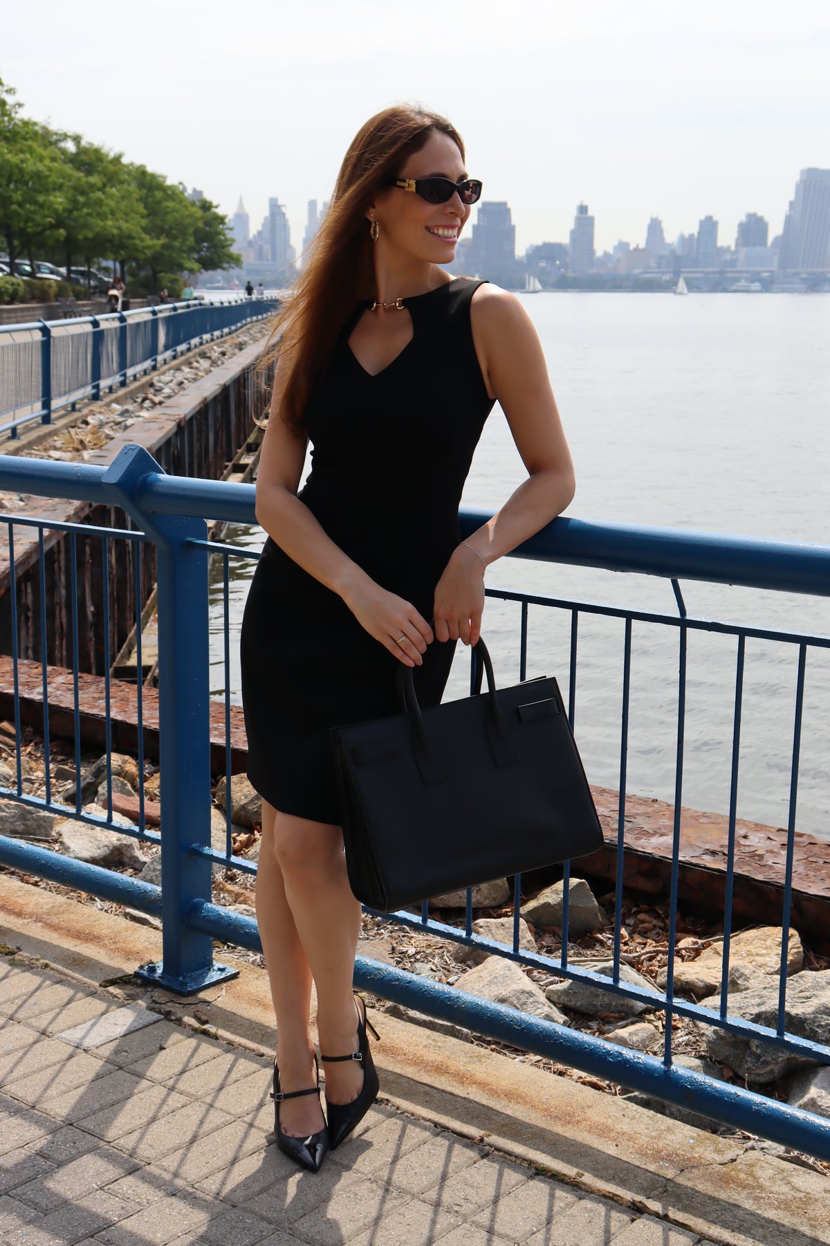 Model wearing our Black Snaffle Bit Keyhole Ponte Dress at the pier! Standing tall in the sun, sporting a classic black bag, heel and sunglasses set with our classic cut dress.