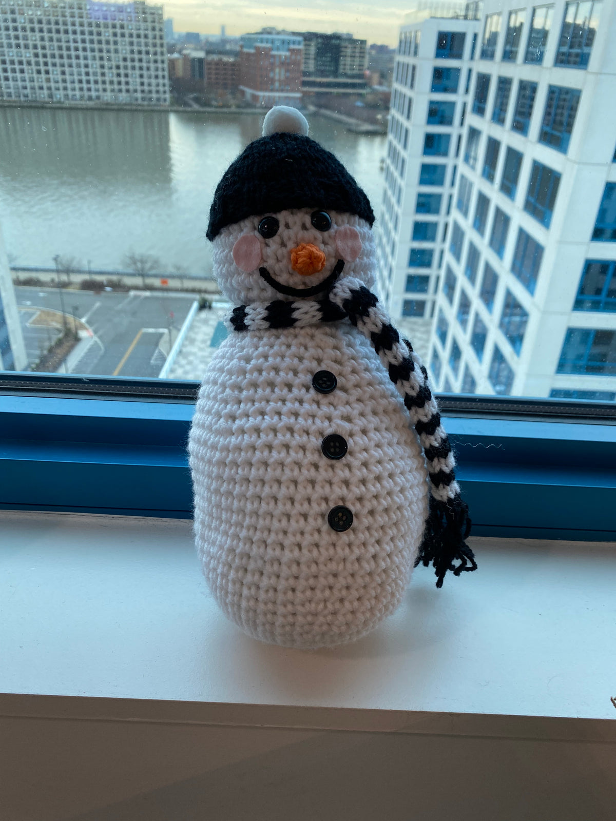 Cute crocheted snowman with black beanie and black and white scarf