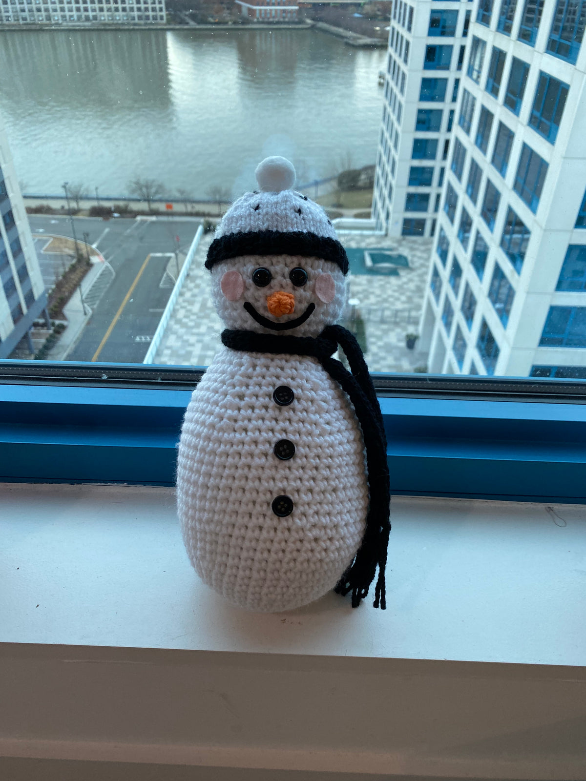 Cute crocheted snowman with plain black scarf and white hat with black hearts