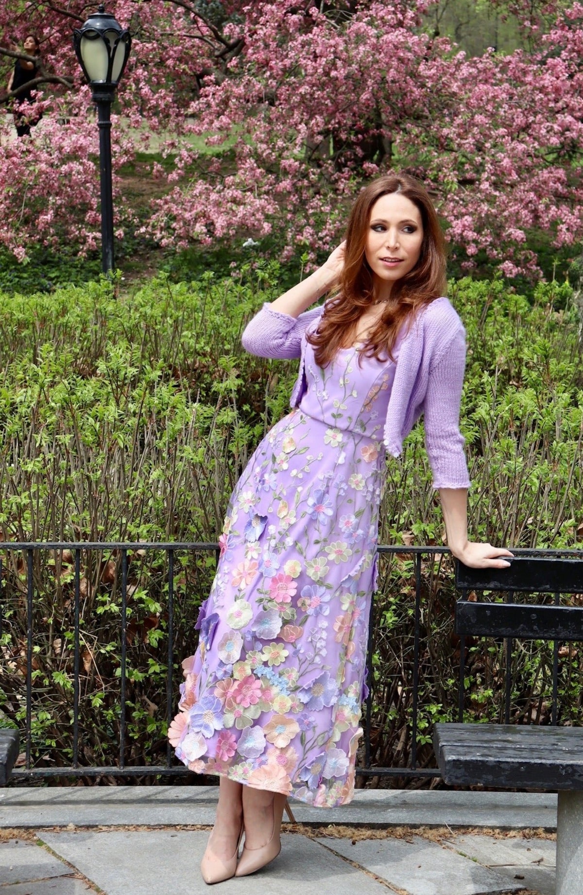 Model in long lilac midi length dress with floral applicqued details with a matching lilac cropped sweater.