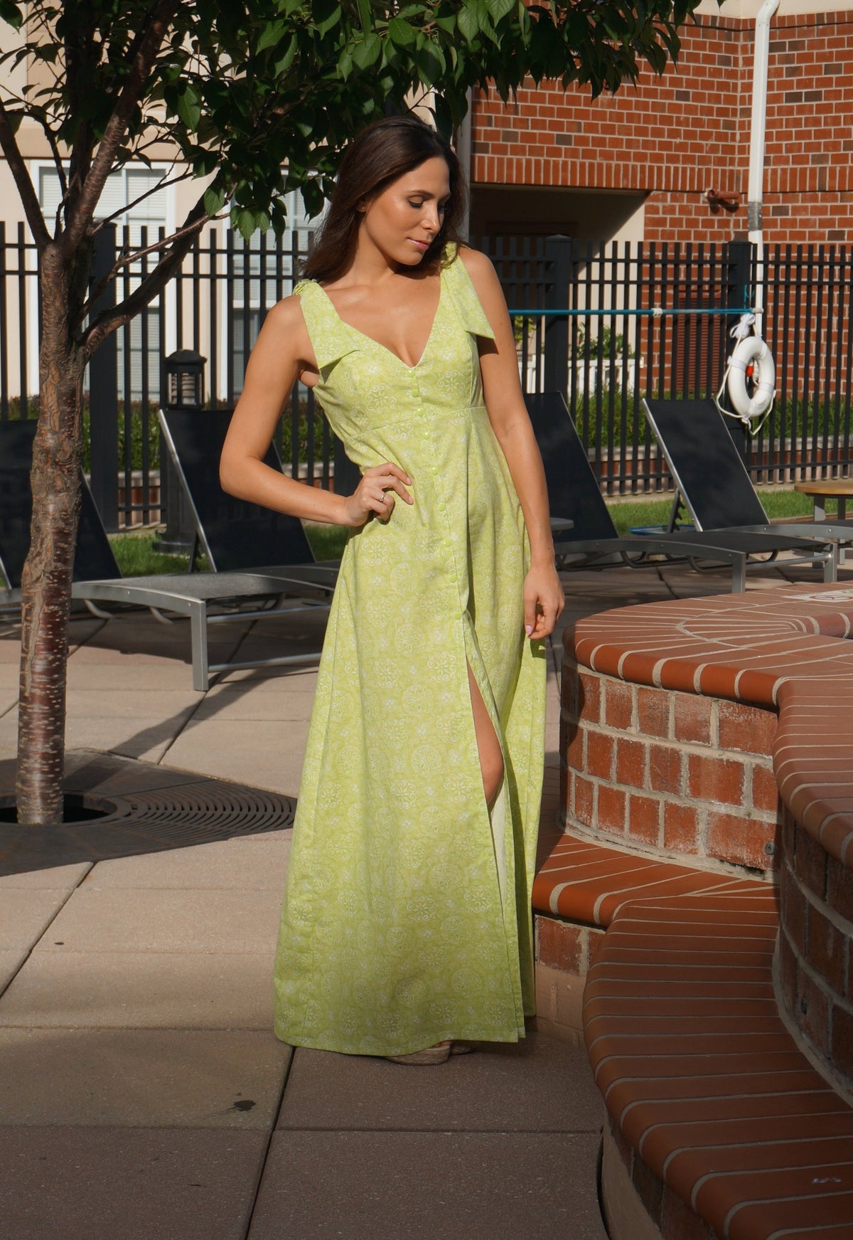 Model wearing a light green maxi dress by the pool.