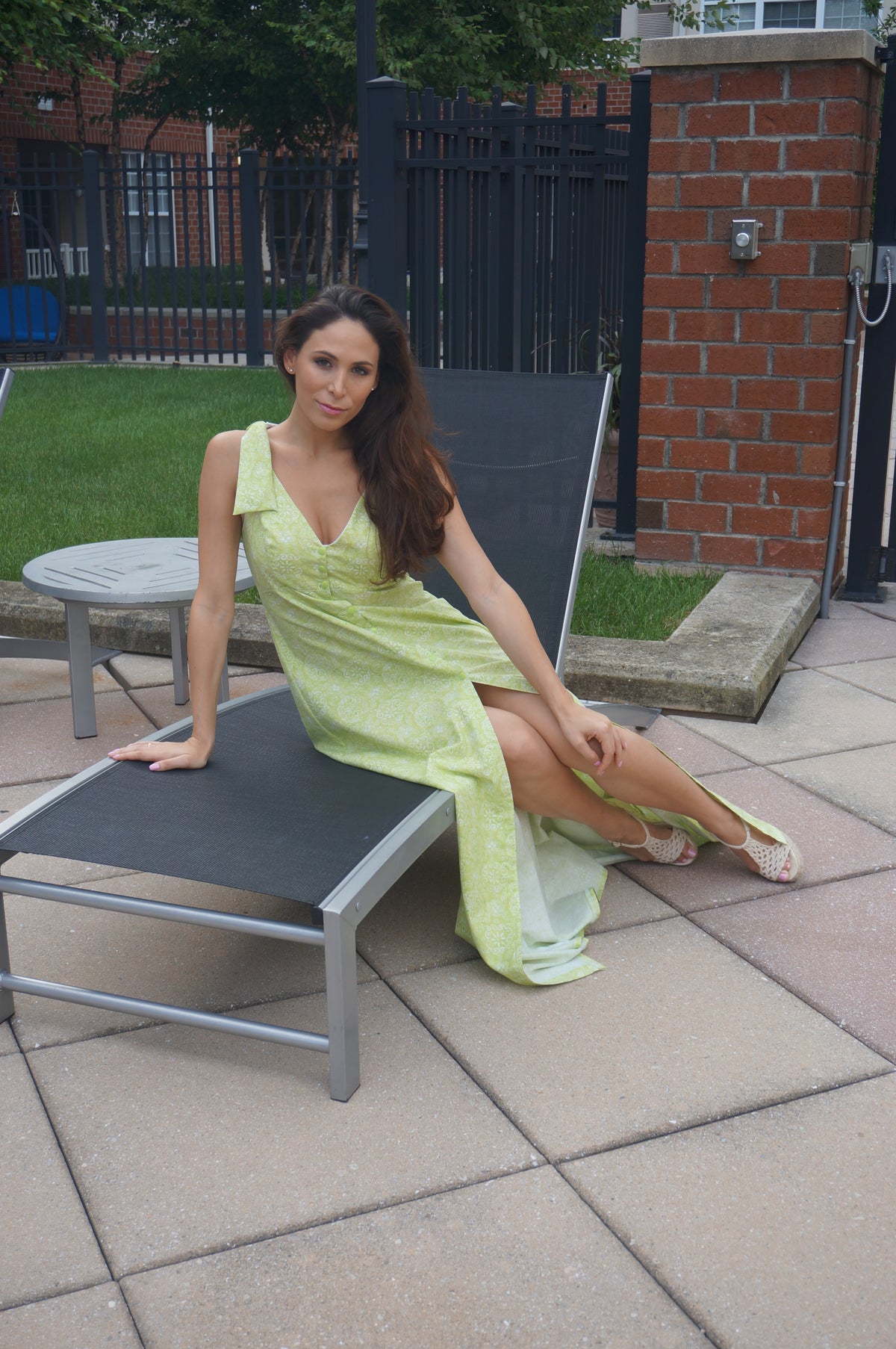 Model wearing a light green maxi dress sitting on a lounge chair.