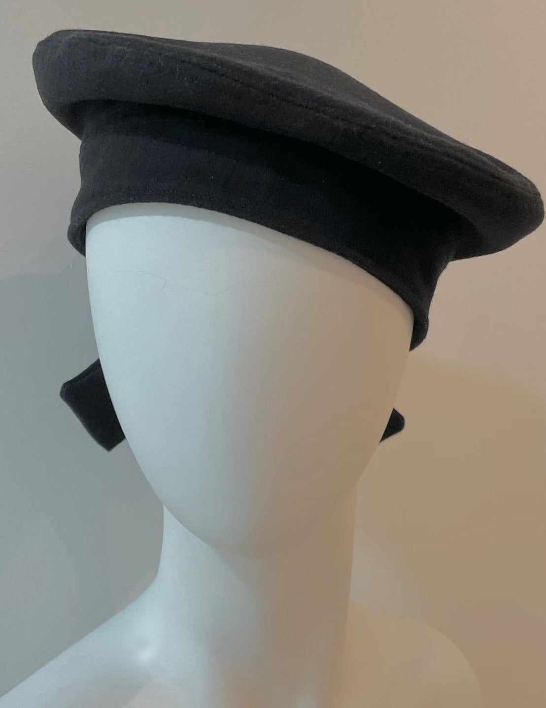 Front of mannequin wearing black bow beret.