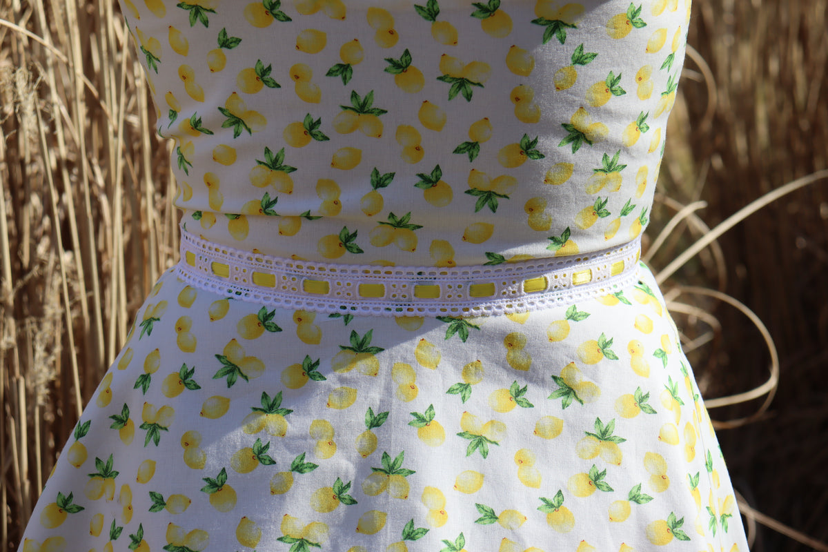 Picture shows detail of lemon print dress at the waist with hay pictured in the background.