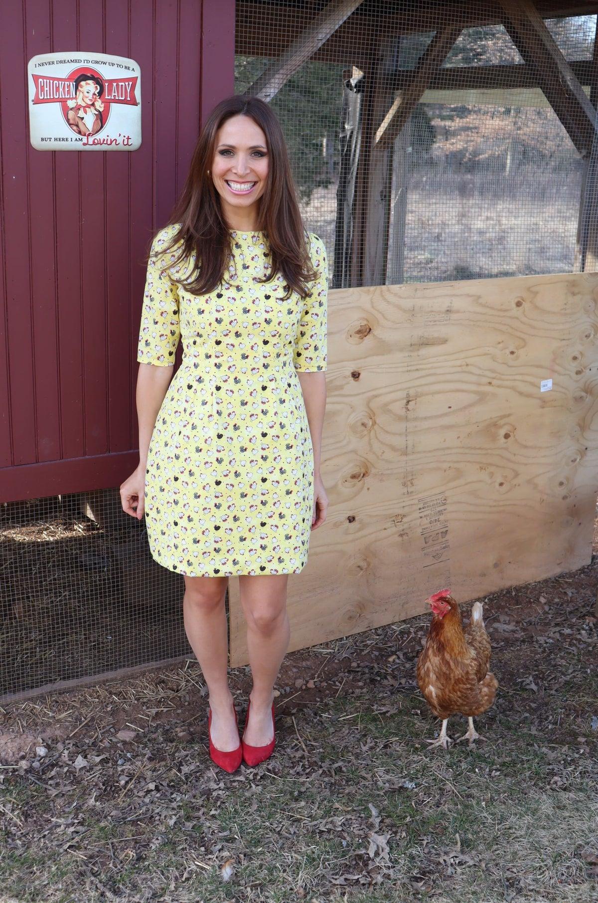 Model in front of chicken coop with a chicken wearing Editorial Chicken Dress,  a cute chicken print classic shift dress.