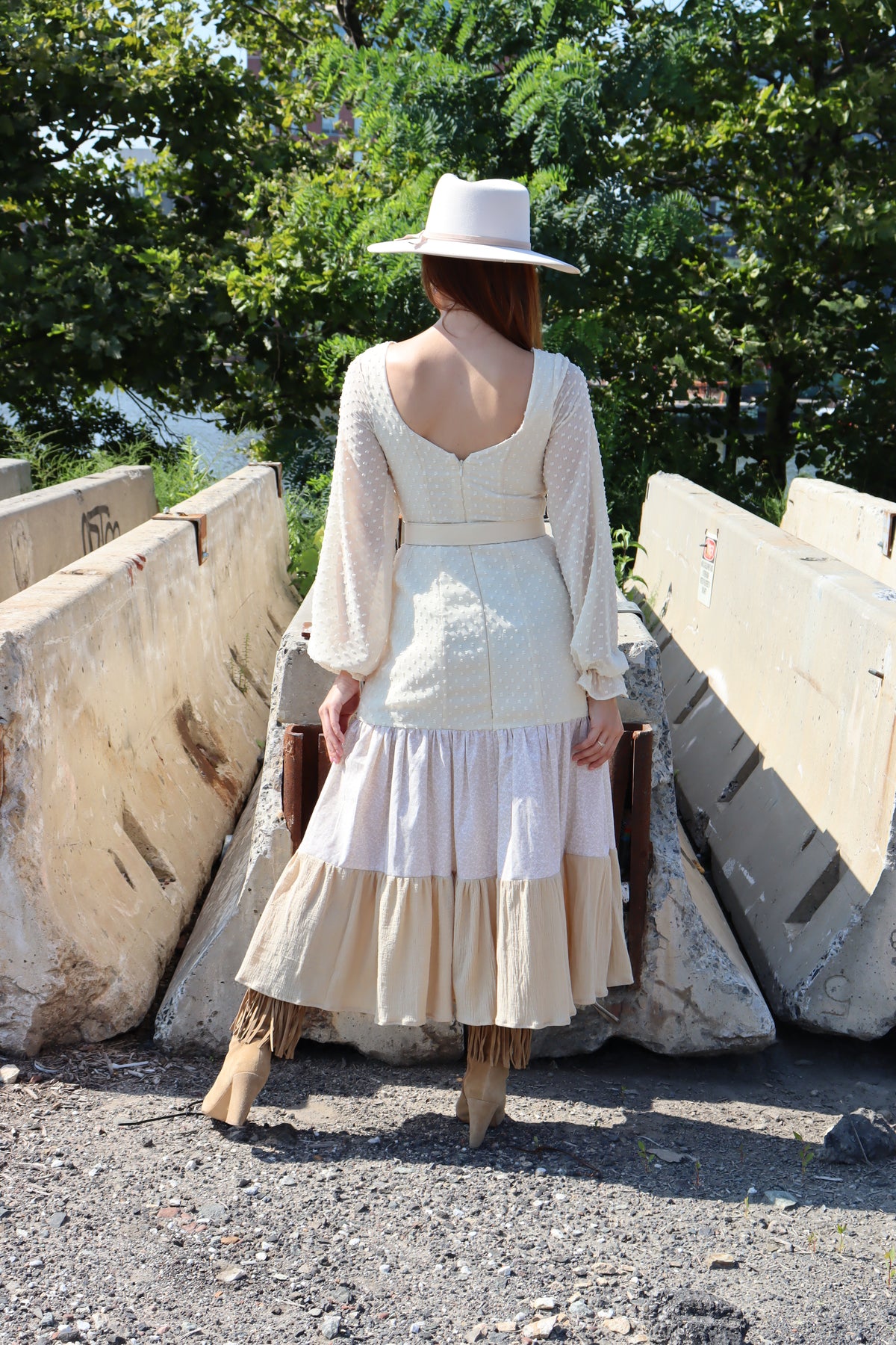 Back of model wearing dress with three different fabrics, Swiss Dot, Calico and Gauze midi dress, a belt and hat.