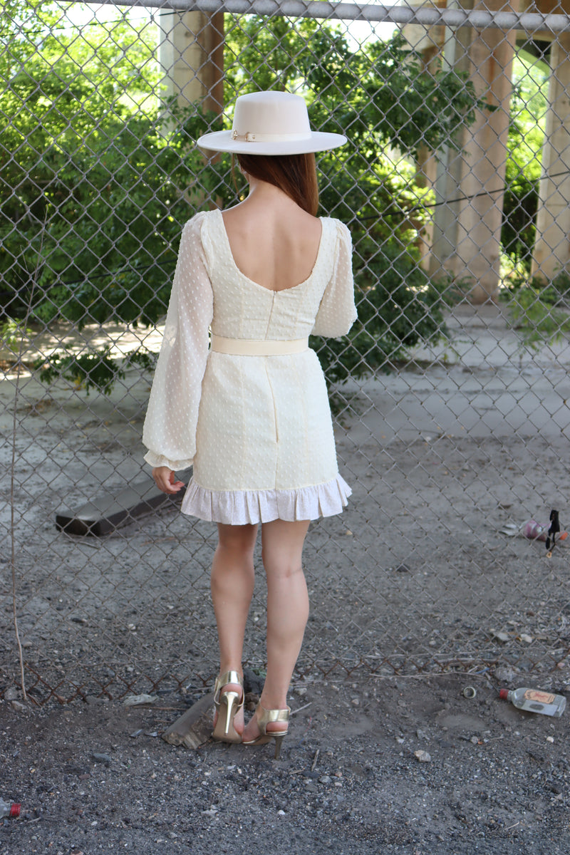 Back of model wearing cream cotton Swiss Dot fabric, cream belt, cream hat.