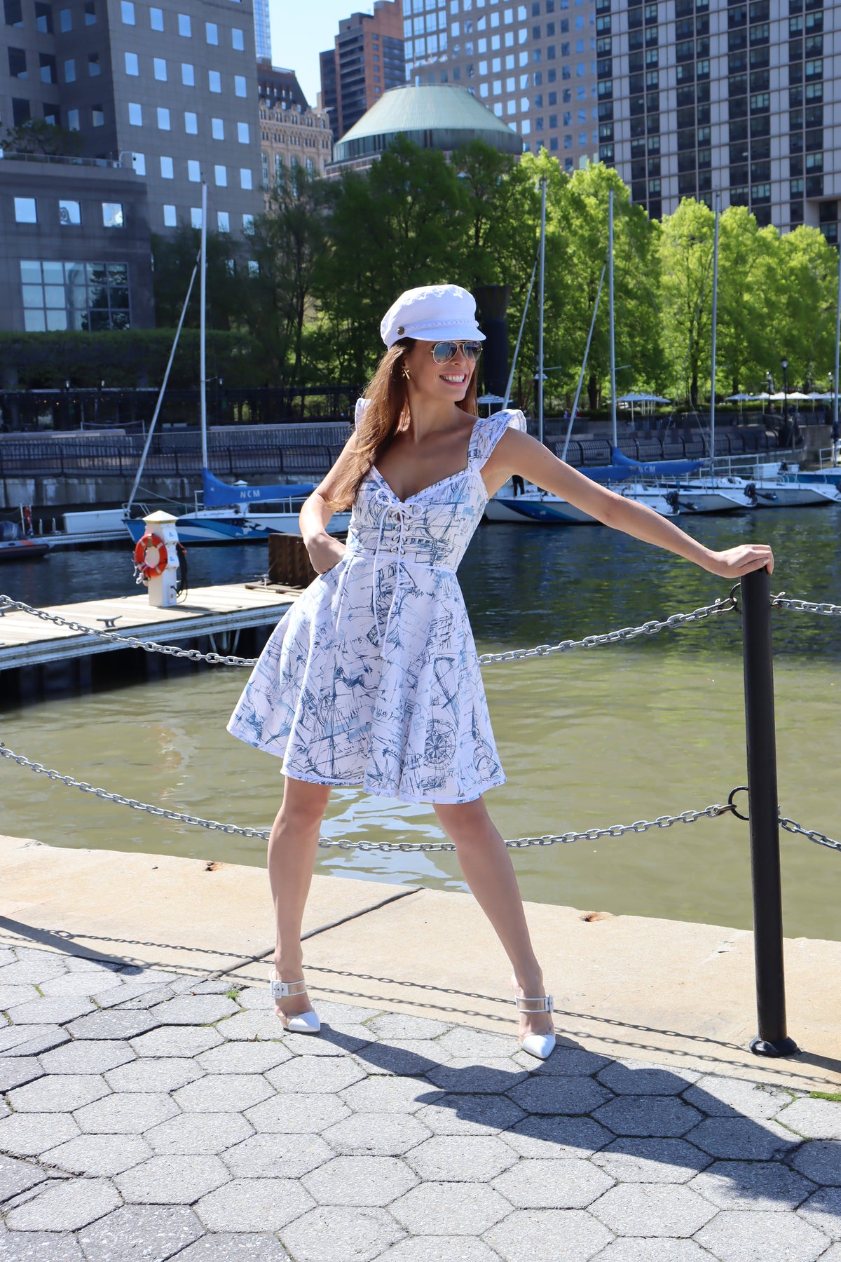 Model wearing heavy toile schooner print and a white hat standing in front of water.