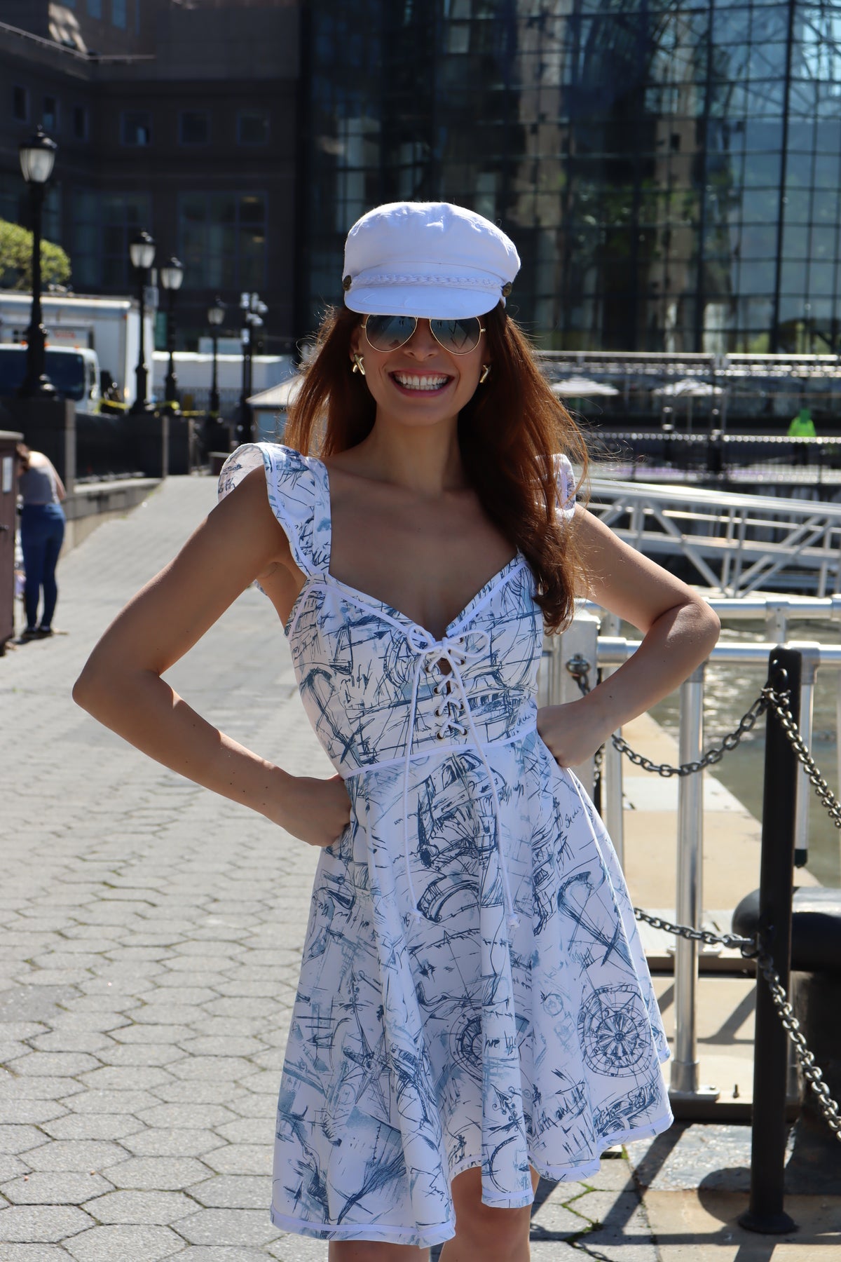 Close up of model wearing heavy toile schooner print and a white hat with both hand on her hips