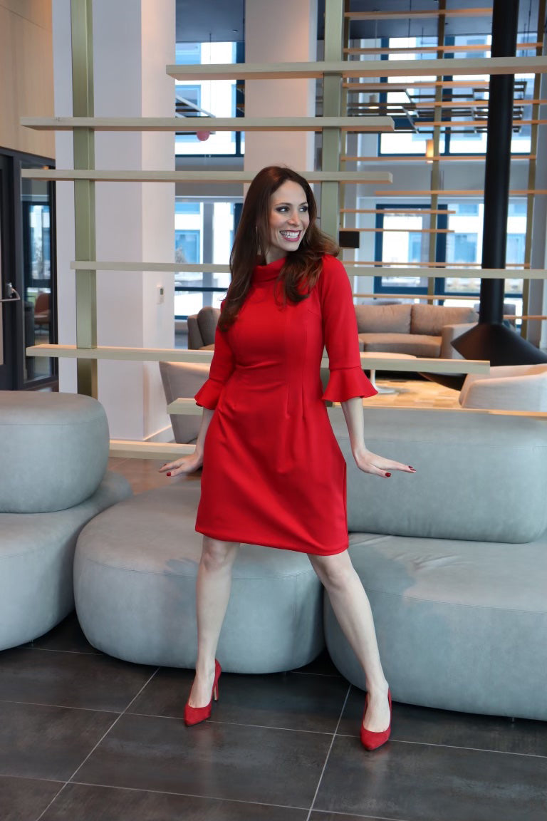 Model wearing a red dress with 3/4 sleeves looking off to the side smiling
